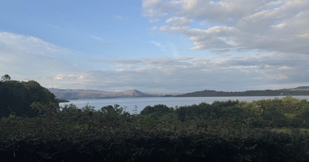 Calm lake beneath distant mountains in evening light