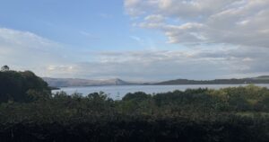 Calm lake beneath distant mountains in evening light